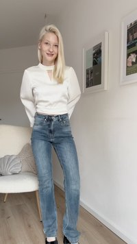 Λευκή μπλούζα μακριά μανίκια με κοψίμα κλειδώματος, συνδυασμένη με ψηλόμεσα μπλε τζιν. Λείος υφασμάτινος χαρακτήρας, εφαρμοστή σχεδίαση και διακριτές λεπτομέρειες.