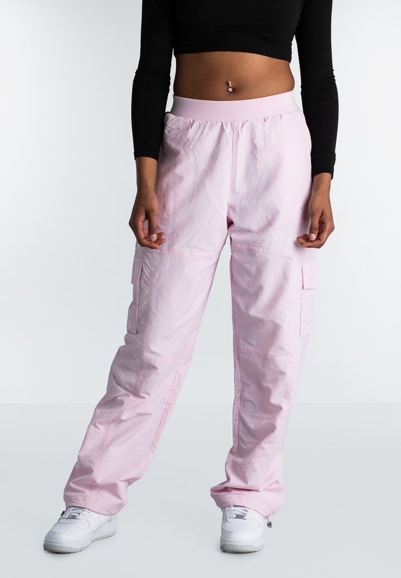 Lichtroze cargobroek van zachte stof, met een elastische tailleband, twee zijzakken en een relaxte pasvorm. Combinatie met witte sneakers.