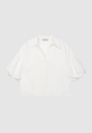 Hvit kortermet bluse med krage, knappestolpe og strukturert stoff. Har lett puffede ermer og perleknapper.