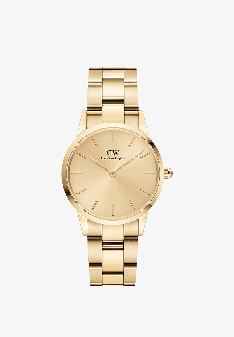 Złoty zegarek z okrągłą tarczą, minimalistycznymi wskaźnikami i metalową bransoletą. Gładka tekstura i polerowane wykończenie, z logo na godzinie 12.