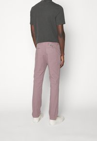 Szara koszulka zestawiona z jasnofioletowymi spodniami. Spodnie mają dwie tylne kieszenie z wielokolorową metką. Całość dopełniają białe trampki.