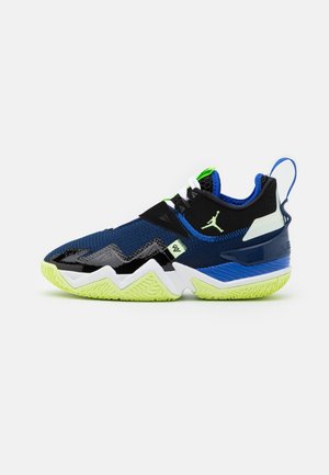 Chaussure de sport basse bleue et noire avec semelle vert néon, semelle intermédiaire blanche et logo Jumpman sur le côté, sur fond blanc.