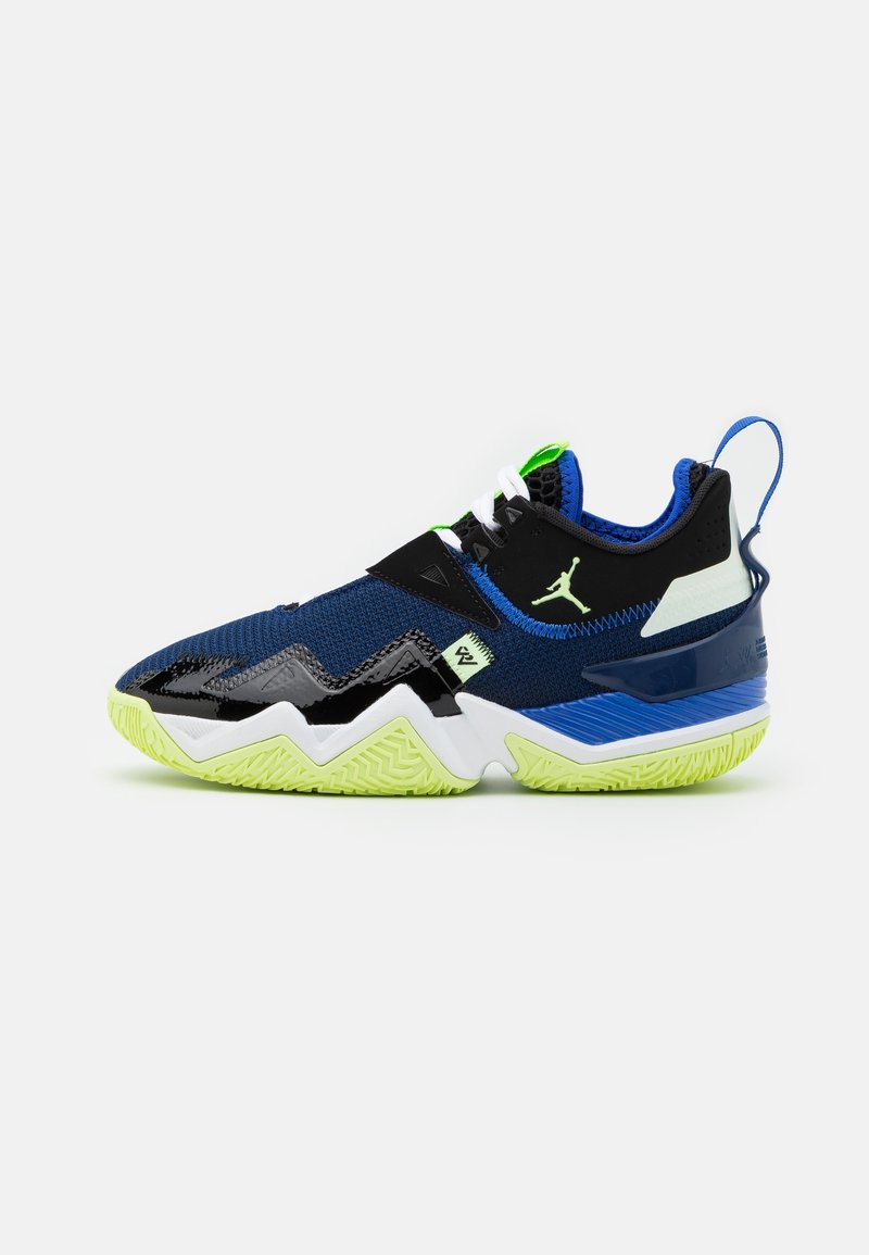 Chaussure de sport basse bleue et noire avec semelle vert néon, semelle intermédiaire blanche et logo Jumpman sur le côté, sur fond blanc.
