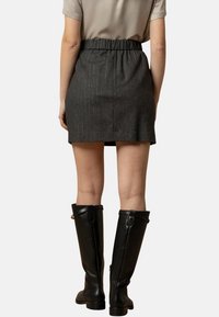 Gonna grigia a righe con cintura elastica, lunghezza al ginocchio. Abbinata a stivali in pelle neri al ginocchio. Texture liscia e design sartoriale.