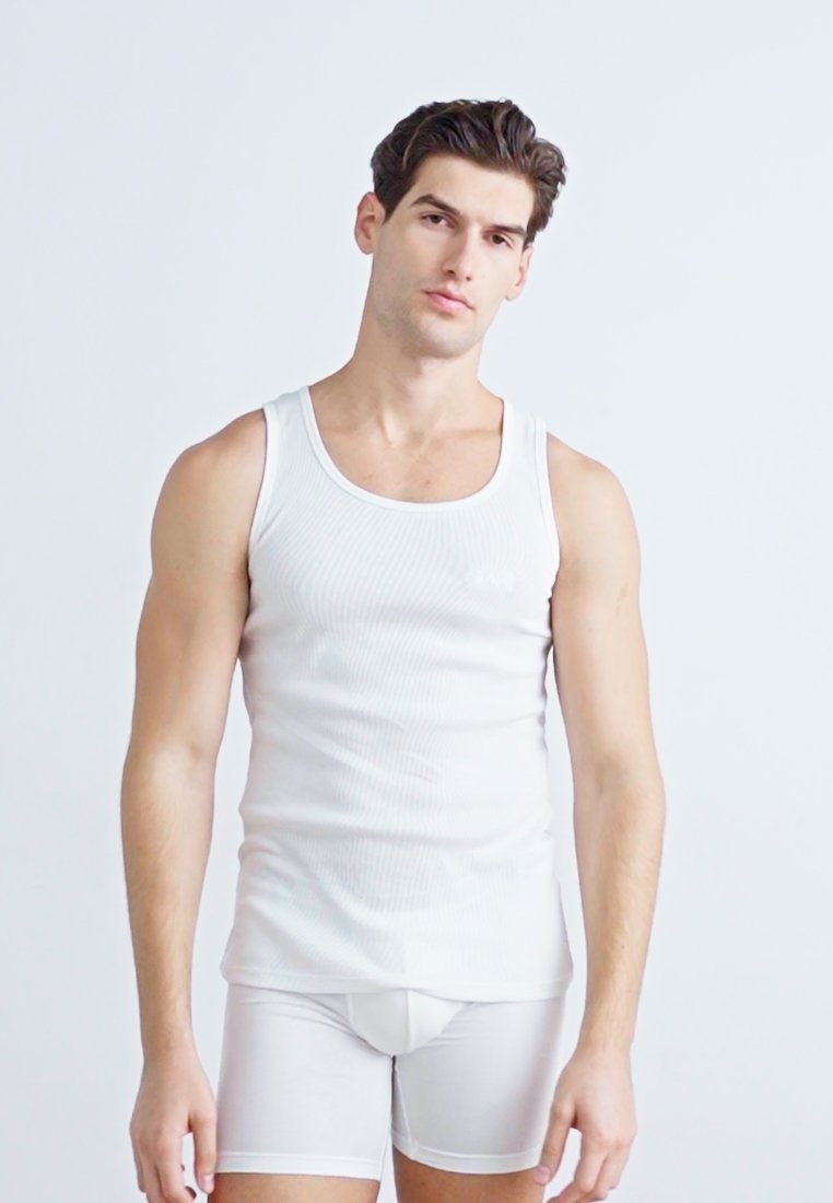Débardeur blanc à côtes avec un col rond, associé à un short boxer blanc ajusté. Texture lisse, branding minimal sur la poitrine.