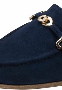 Chaussure en daim bleu marine à enfiler avec un bout arrondi, ornée d'un accent en métal doré et de coutures contrastantes le long des bords.