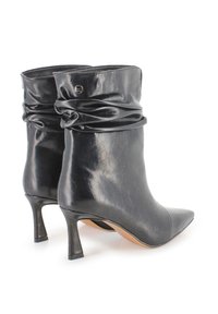 Botines de cuero negro con punta afilada, diseño superior arrugado y tacón stiletto de 6.5 cm. Presentan un logotipo en el lado.