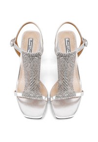 Sandali slingback argentati con una fascia decorata e testurizzata, design a punta quadrata e finitura metallica liscia.