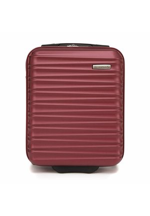 Valigia rigida color bordeaux con texture a righe verticali, una placca logo argentata e una maniglia superiore, progettata per resistenza e comodità durante i viaggi.