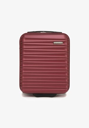 Valise rigide bordeaux avec texture rainurée verticale, plaque de logo argentée et poignée sur le dessus, conçue pour la durabilité et la commodité lors des voyages.