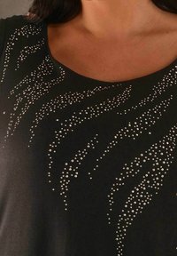 Top nero con scollatura a barco e un design testurizzato di strass lucenti disposti in pattern ondulati.