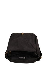Black canvas messenger bag with a flap, features a visible zipper and button closure, and interior label. Soft texture and minimalist design.