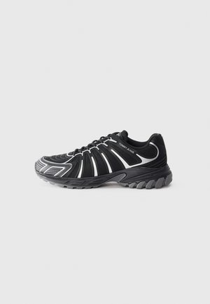 Black athletic shoe with white accents, featuring a textured upper, curved design, and a rubber sole with prominent treads for traction.