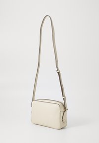 Borsa a tracolla in pelle beige chiaro con una superficie liscia, forma rettangolare e rifiniture scure a contrasto. Presenta una tracolla regolabile.