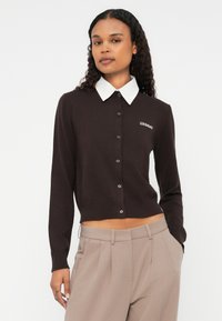 Cardigan marron avec un col blanc, présentant un devant à boutons et un ourlet côtelé. Logo "2ND DAY" brodé sur le côté gauche.