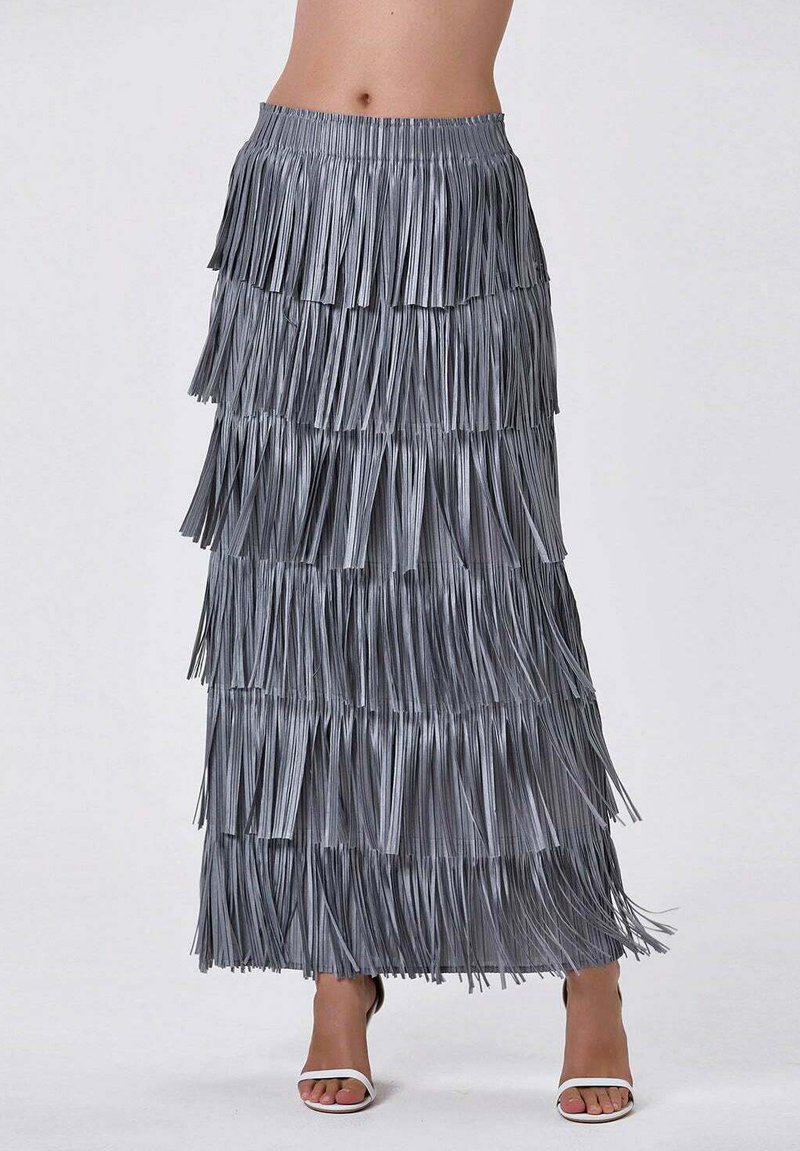 Jupe longue en fringes argentées avec un design superposé. Fabriquée en matériau brillant, elle présente plusieurs niveaux de franges. Associée à des talons blancs.