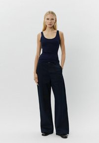 Maiou de marină și pantaloni largi dintr-un material neted; caracterizează un design ajustat, siluetă dreaptă și închidere cu buton.