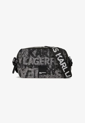 Prostokątna torba na ramię z czarno-szarym abstrakcyjnym wzorem tekstowym, z zamkiem błyskawicznym i szerokim czarnym paskiem z białym logo "KARL LAGERFELD".