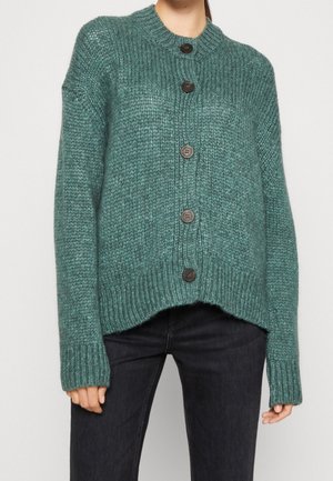 Gilet en tricot turquoise avec un col rond, cinq boutons foncés, texture côtelée et coupe décontractée. L'ourlet court ajoute de la dimension.