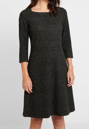 Vestito nero lavorato a maglia con texture, scollo quadrato, maniche a tre quarti e gonna svasata, con dettagli di motivo sottili.