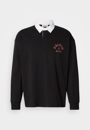 Črna polo majica z dolgimi rokavi in belim ovratnikom, z majhnim rdečim logotipom natisnjenim na prsih in klasičnim gumbnim izrezom.