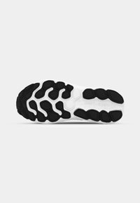 Black and white athletic shoe sole with a textured pattern and cushioned, segmented design for traction and support. "new balance" logo visible.