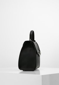 Sac en cuir noir avec une forme triangulaire structurée, une anse supérieure et des détails en métal argenté. Texture lisse avec un design minimaliste.