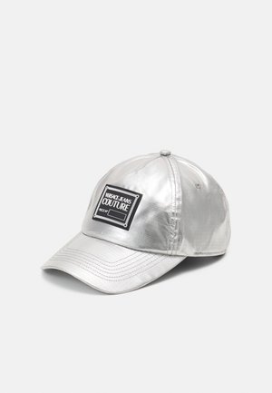 Silberne metallic Baseballkappe mit aufgenähten Paneelen und einem rechteckigen schwarzen Patch mit der Aufschrift „VERSACE JEANS COUTURE“ vorne.