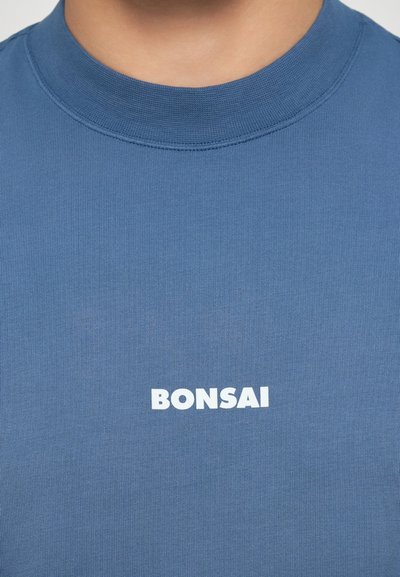 Modrá bavlněná tričko s ribovanou strukturou a kulatým výstřihem, na přední straně s bílým logem "BONSAI".