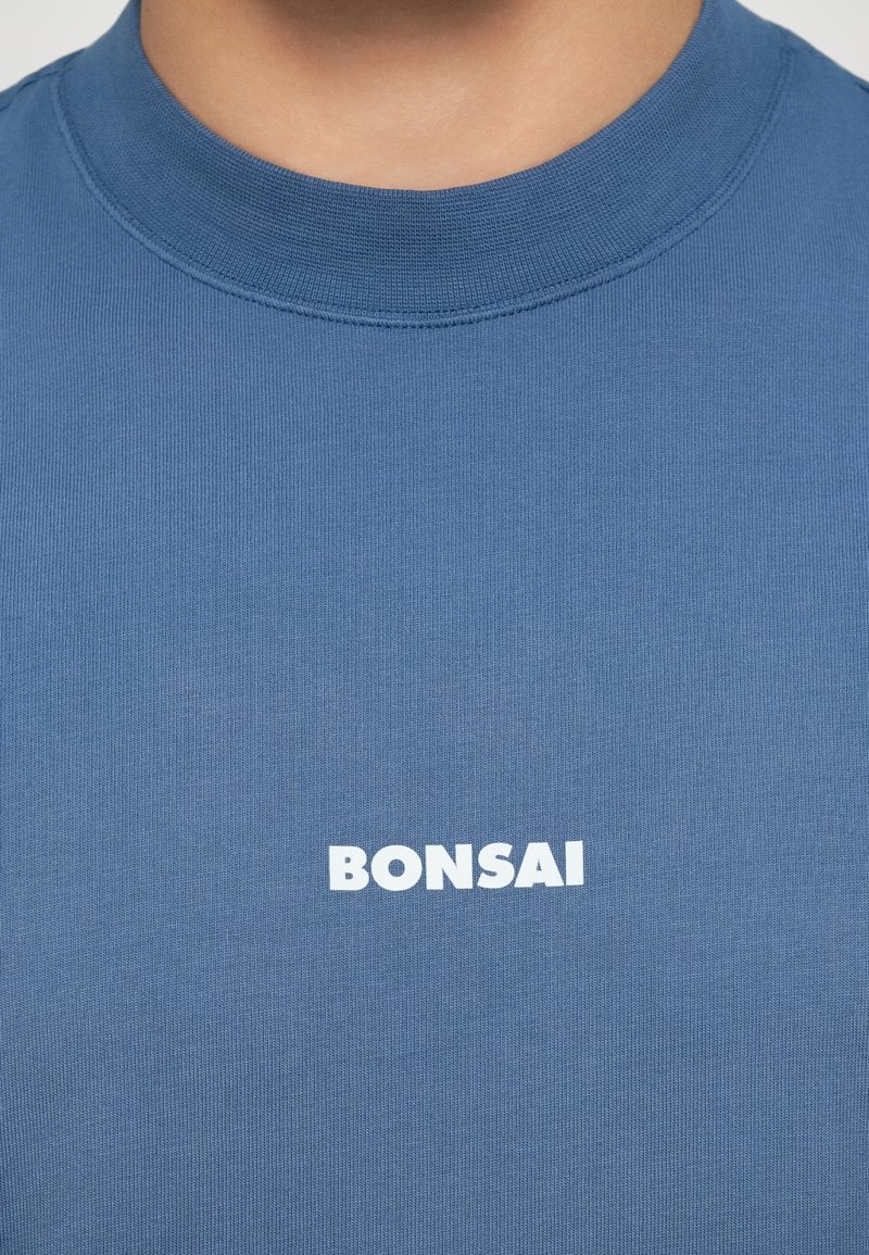 Blue cotton t-shirt with a ribbed texture and a crew neckline featuring a white "BONSAI" logo on the front.