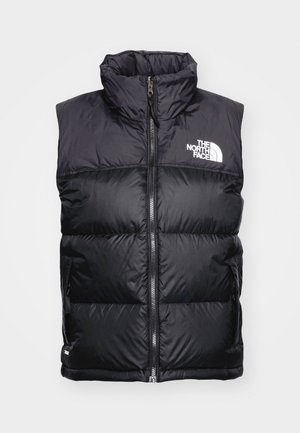 Gilet matelassé noir avec col haut, fermeture éclair et logo blanc sur la poitrine. Comprend des sections rembourrées pour l'isolation et des poches latérales.