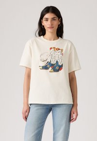 T-shirt en coton couleur crème à manches courtes, présentant un graphisme de bottes de cowboy et d'un chapeau dans des couleurs vives et des motifs détaillés.