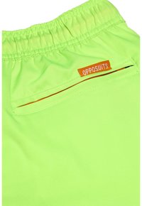 Neon žali šortai su elastine juosta ir oranžine "OPPOSUITS" etikete. Yra kišenė su kontrastinga oranžine apdaila.