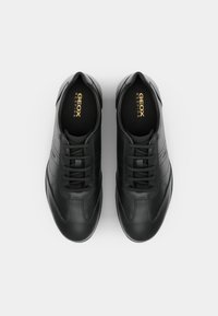 Sneakers negre din piele cu vârf rotund, șase treceri pentru șireturi, textură netedă și cusături laterale subtile. Logo imprimat pe tălpile interioare.