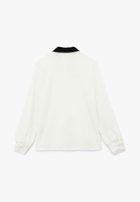 Blusa blanca de manga larga, con cuello negro, puños abotonados y una textura suave, que presenta una silueta recta y sin patrones visibles.