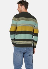 Gestrickter Pullover mit horizontalen Streifen in Teal, Senfgelb und Dunkelgrün. Mit gerippten Bündchen und Saum, im Rundhalsausschnitt-Design. Getragen mit blauen Jeans.