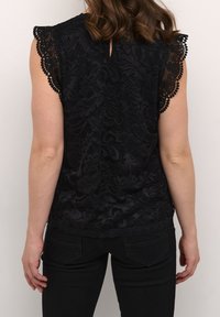 Czarna koronkowa bluzka z falbaniastymi rękawami, kwiatowymi wzorami i wycięciem z tyłu, w połączeniu z czarnymi dżinsami. Teksturowany i dopasowany krój.
