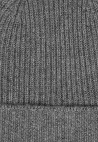 Grijze gebreide beanie van gestructureerde wol, met een geribd patroon en een omgeslagen manchette aan de basis voor warmte en comfort.