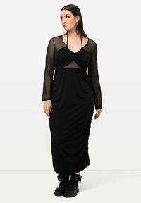 Schwarzes Maxikleid mit langen transparenten Ärmeln, gerafftem Oberteil und verstellbaren Trägern. Es hat eine glatte Textur und eine figurbetonte Silhouette.