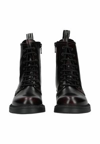 Botines de cuero negro con acabado brillante, con cordones delanteros y cremallera lateral, suela texturizada y lengüeta en la parte trasera.