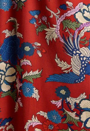 Rød stof med indviklede blomsterprint i blå, hvid, lyserød og grøn, med stiliserede fugle og blade spredt over overfladen.