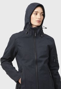 Chaqueta con capucha de color azul marino con un acabado texturizado, cierre de cremallera completo, cordones ajustables y bolsillos laterales con cremallera.