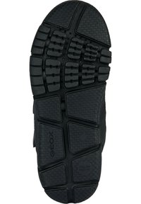 Semelle en caoutchouc noir avec un motif de grip texturé, comprenant des sections surélevées et des formes géométriques. Comprend une marque sur le côté.
