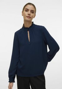 Navyblauw blouse met een uitgerokken kraag en een sleutelgatopening, met lange mouwen en gesmokkeld manchet, gemaakt van een gestructureerde stof.