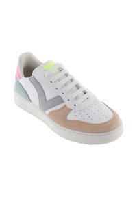 Sneaker bianca con tocchi di camoscio beige, grigio, blu e rosa, lacci bianchi e perforazioni sulla punta, esposta su uno sfondo bianco.