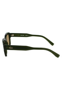 Occhiali da sole in plastica verde con montatura quadrata, lenti marroni e dettagli testurizzati sottili sulle aste. Logo Lacoste impresso sul lato.