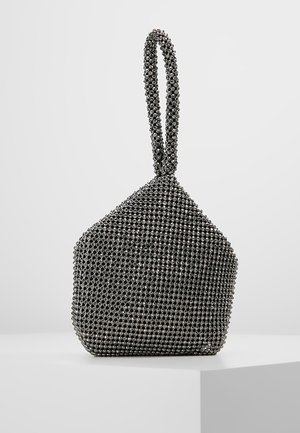 Musta helmikoristeinen rannepussi, jossa lenkkikahva ja geometrinen trapetsin muoto, esillä valkoisella pinnalla yksinkertaisen taustan edessä.