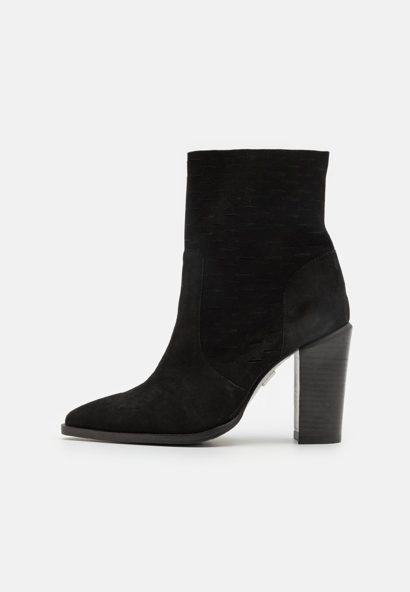 Botte cheville en daim noir avec bout pointu, dessus texturé et talon haut épais sur fond blanc.