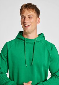 Grüne Kapuzenjacke mit Kordelzug, aus weichem Stoff. Verfügt über einen lockeren Schnitt und Raglanärmel, zeigt eine glatte Textur und eine einfarbige Optik.
