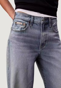 Jeans di denim blu chiaro a vita alta, con un'etichetta Calvin Klein sulla tasca posteriore e sottili dettagli consumati sul tessuto.